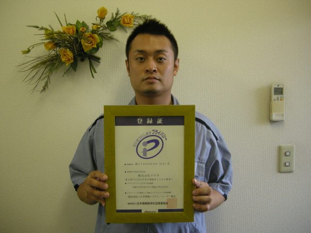梱包、保管、発送代行のお客様。プライバシーマーク登録証を手にした様子。