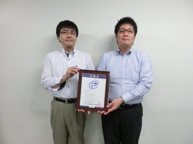 人材派遣のお客様。プライバシーマーク登録証を手にした様子。