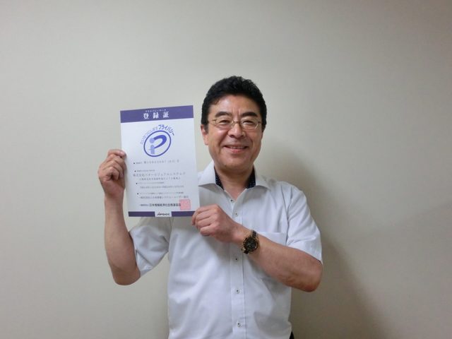 HP作成、システム管理、システム開発のお客様。プライバシーマーク登録証を手にした様子。